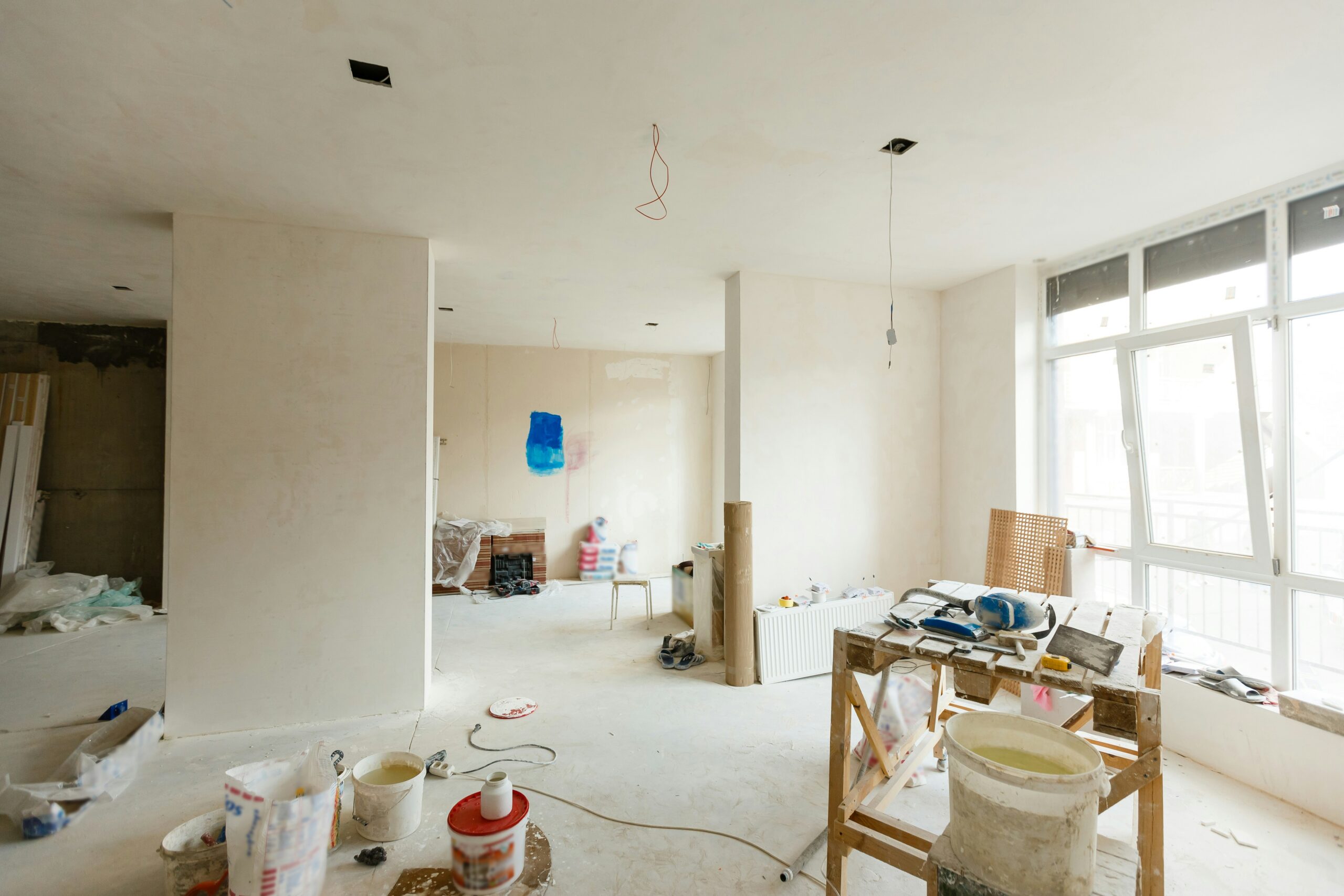 House restoration - freshly plastered interior with paint buckets, a trestle, and a blue test patch on the wall