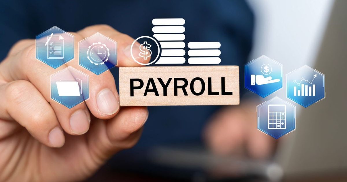 Hand holding a wooden block that reads PAYROLL beside pay, time, and calculator icons